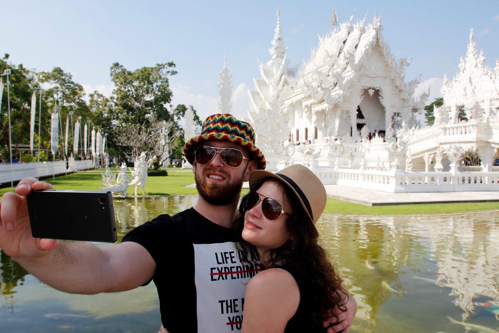 Tourists pose for a selfie outside Wat Rong Khun in Chiang Mai, Thailand.