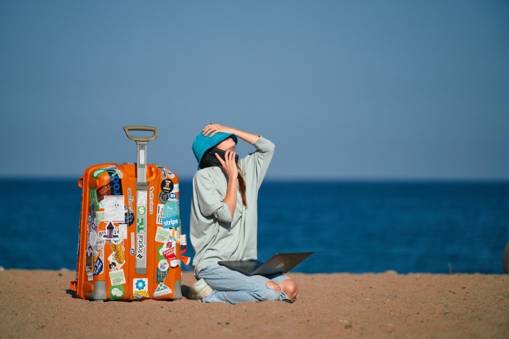 Girl sitting on beach working at her remote job while on vacation