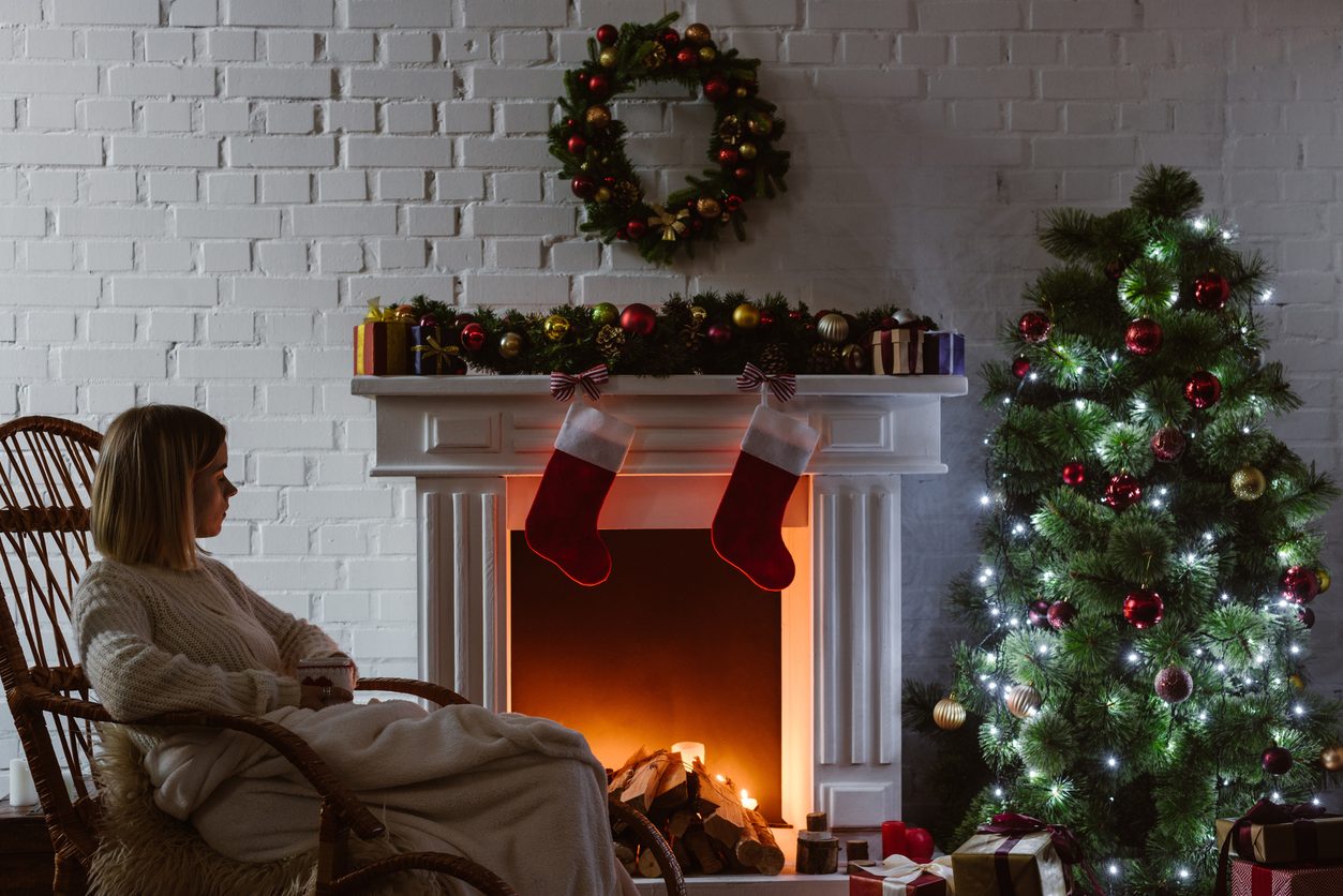 A woman relaxing at home on Christmas. Concerns about inflation are a reason fewer Americans are making holiday travel plans. 