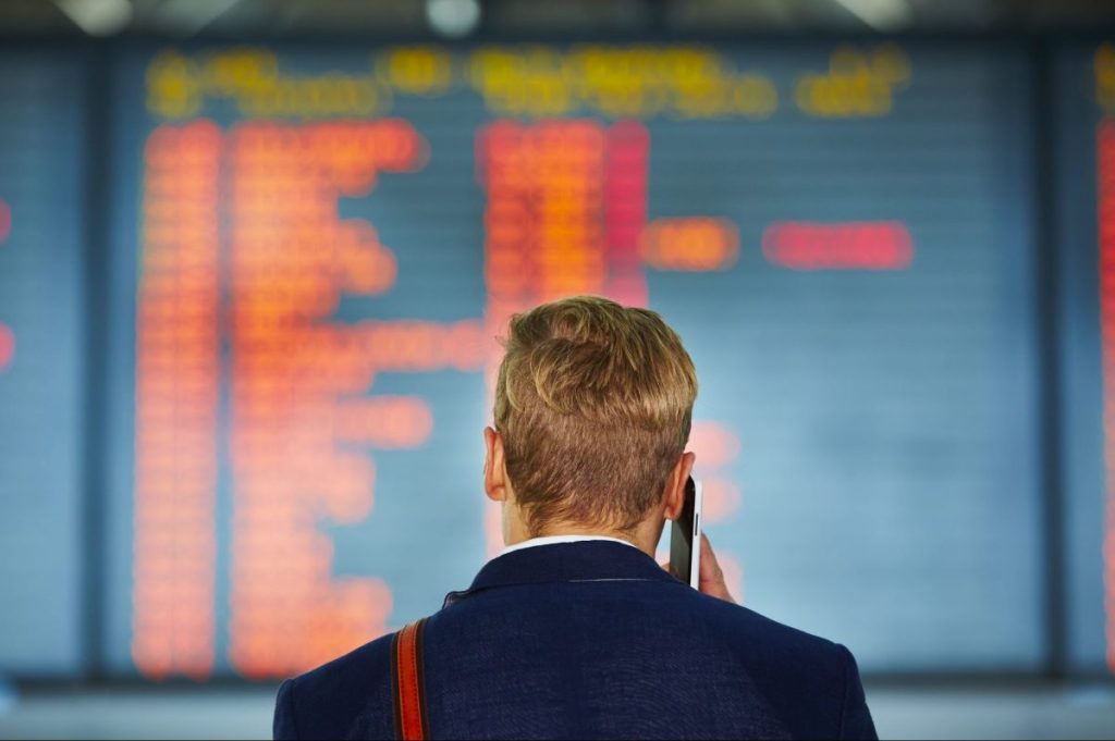 Flyer in front of a board showing flight cancellations.