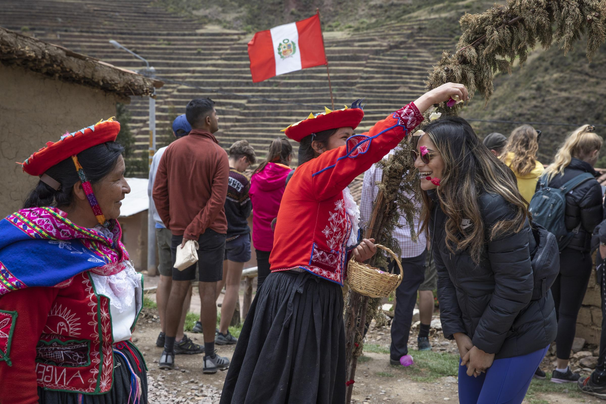 Peru Sacred Valley Pottery Co-op Welcome Female Traveler Interacting Flowers. Source: G Adventures