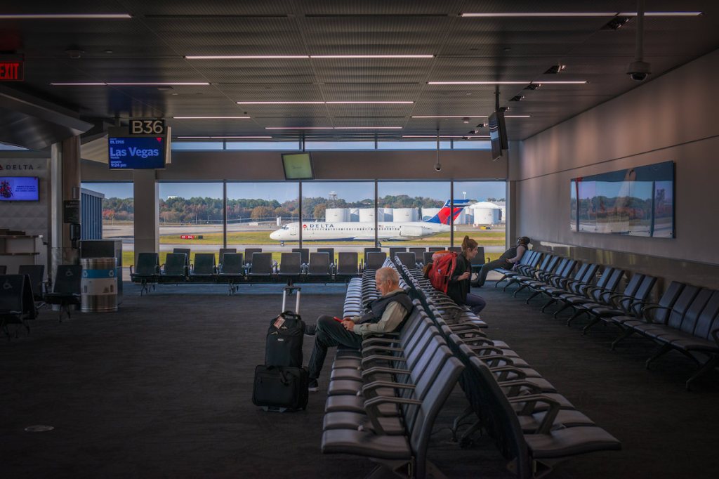 A taxiing Delta plane seen from an airport gate area.