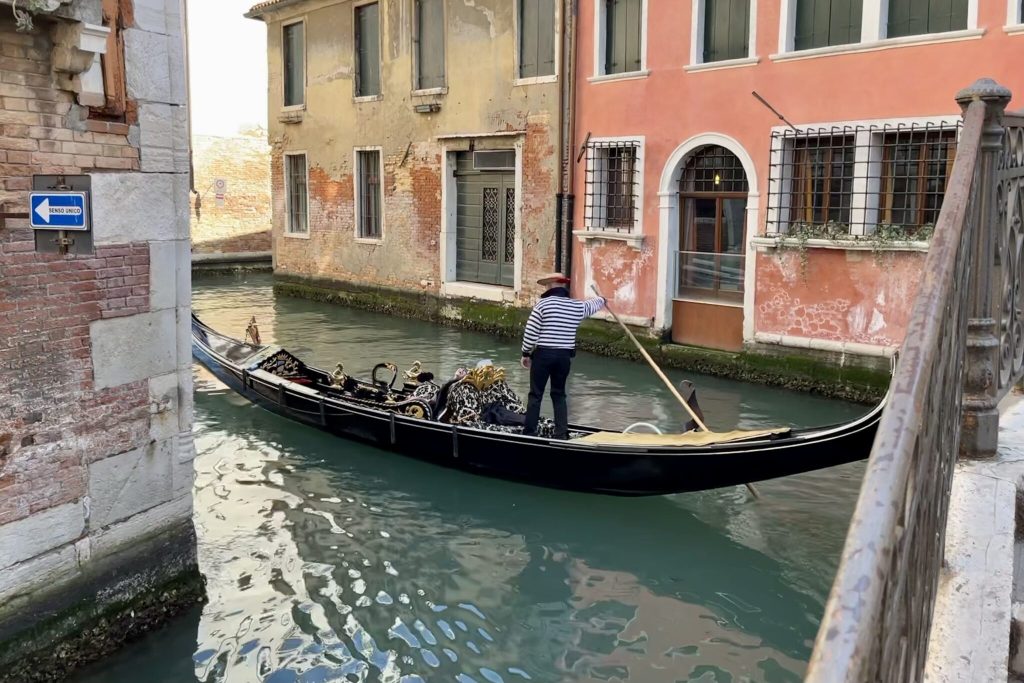 Tourists and a gondolier on a canal in Venice, Italy.