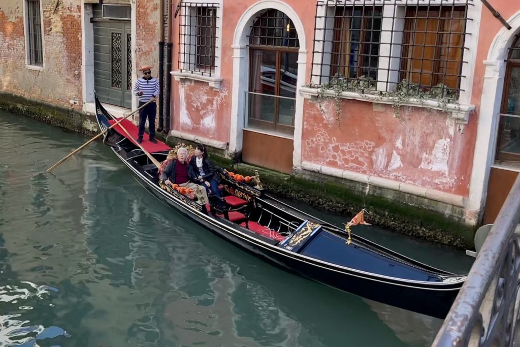 Tourists and a gondolier on a canal in Venice, Italy.