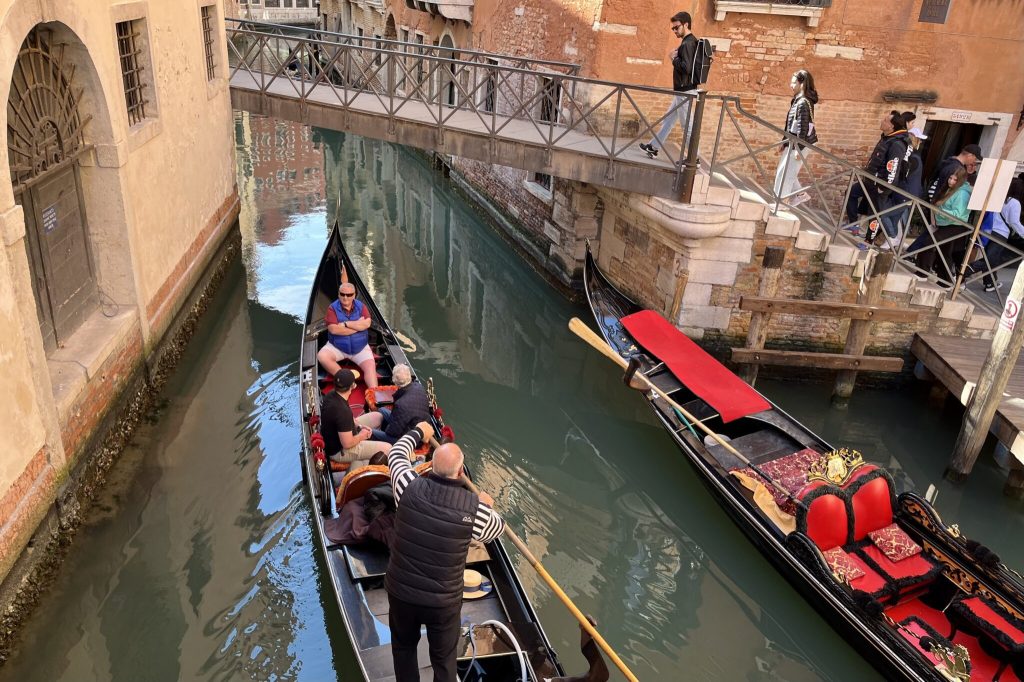 Tourists and a gondolier on a canal in Venice, Italy.