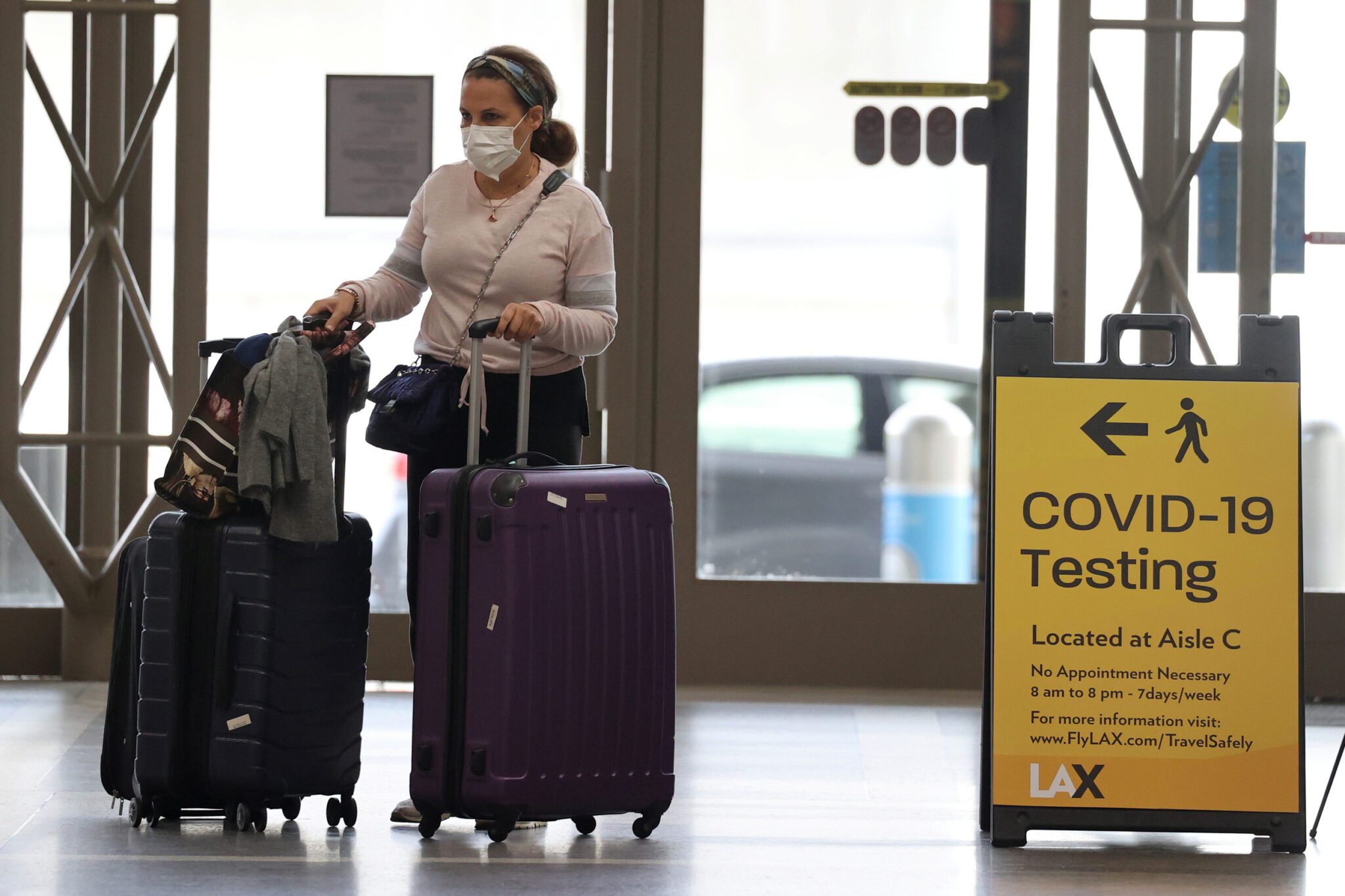 A file photo of a woman walking past a coronavirus testing sign at Tom Bradley international terminal at LAX airport. The U.S. dropped many remaining rules around Covid and travel this week. 