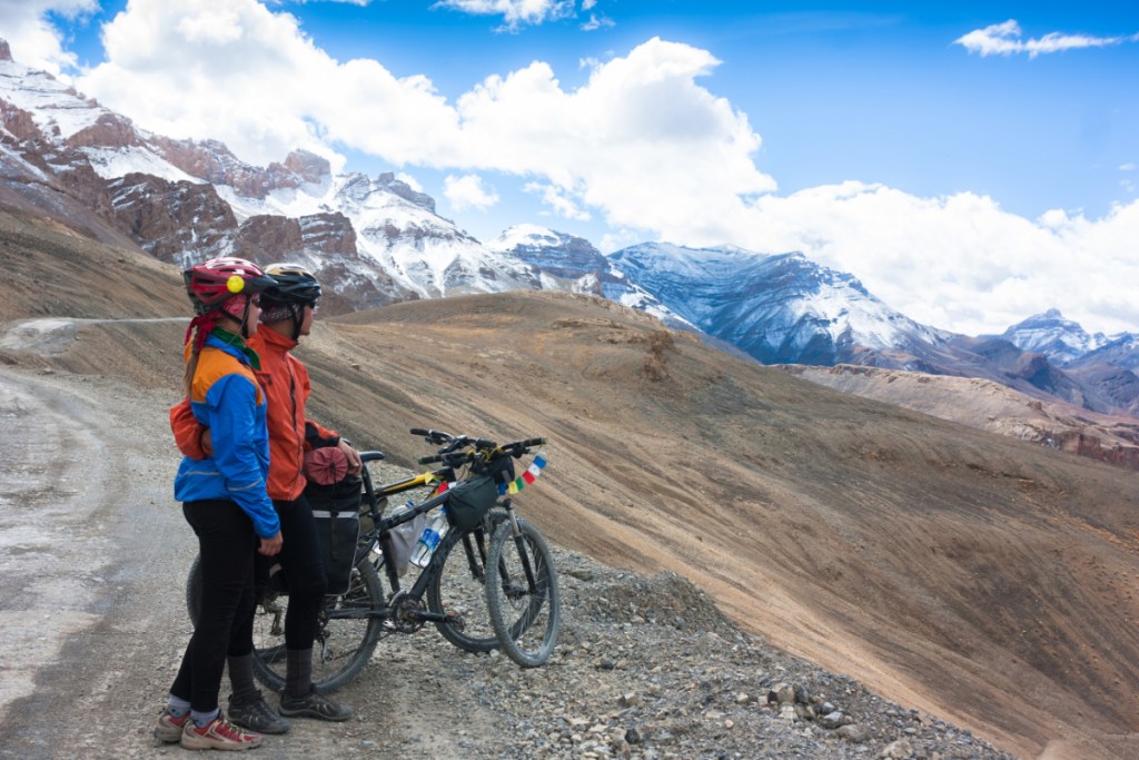 Happy cyclist couple standing on mountains road. Himalayas, Jammu and Kashmir State, North India