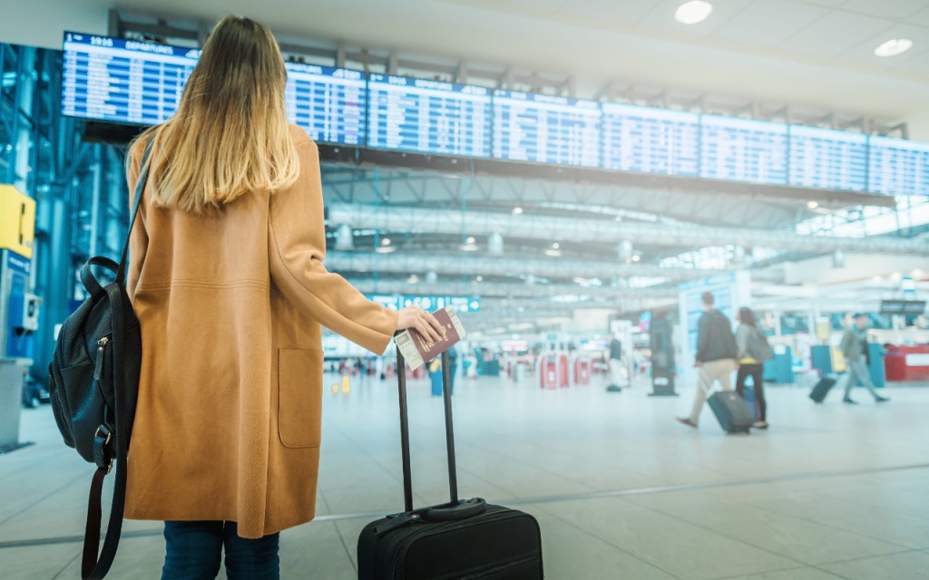 A business traveler stands with her bag in an airport.