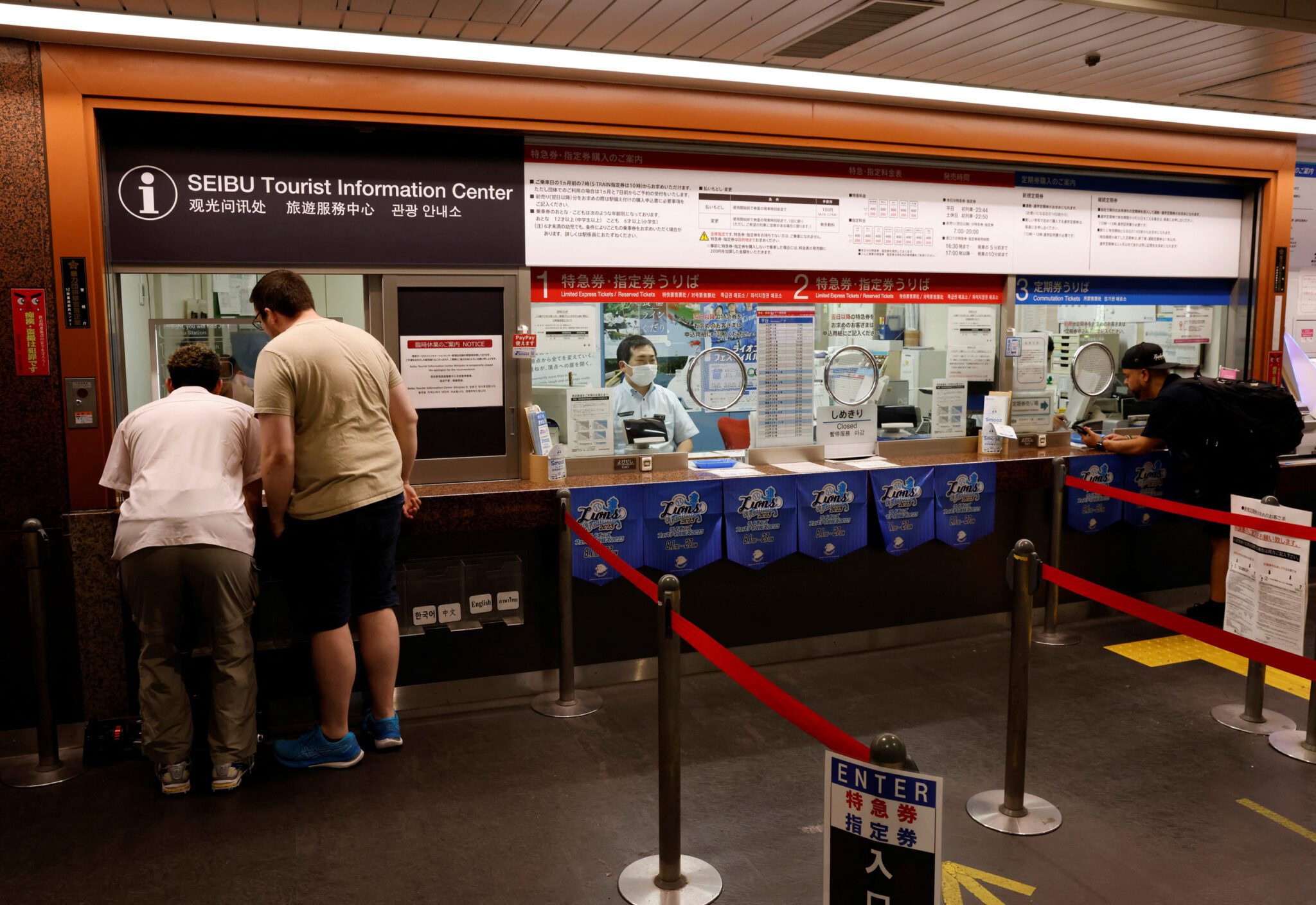 Tourists use an automated translation window in Tokyo's Shinjuku rail and subway station. 