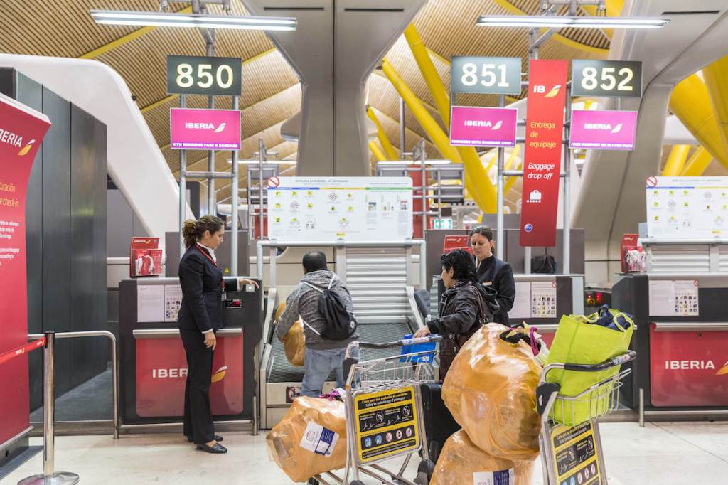 Travelers drop bags at an Iberia counter