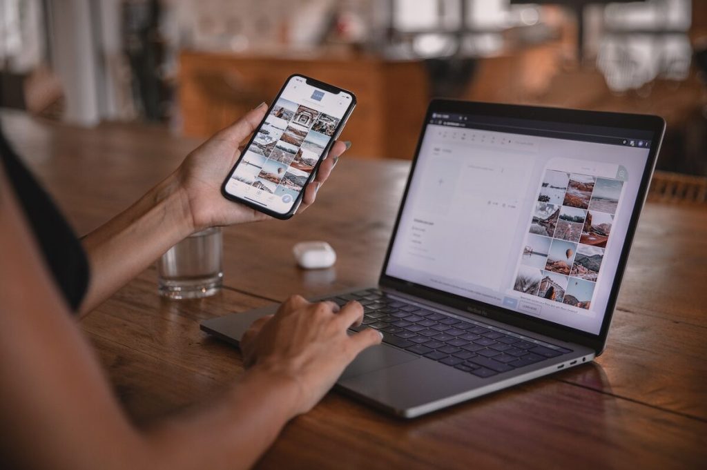 A traveler looking at images on a phone and computer at the same time.