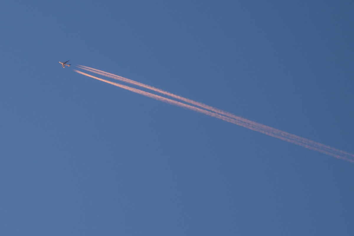 Contrails tail a plane. (Caribb/Flickr)