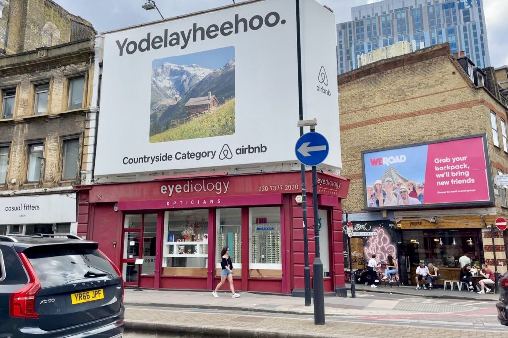 A street scene with an Airbnb billboard