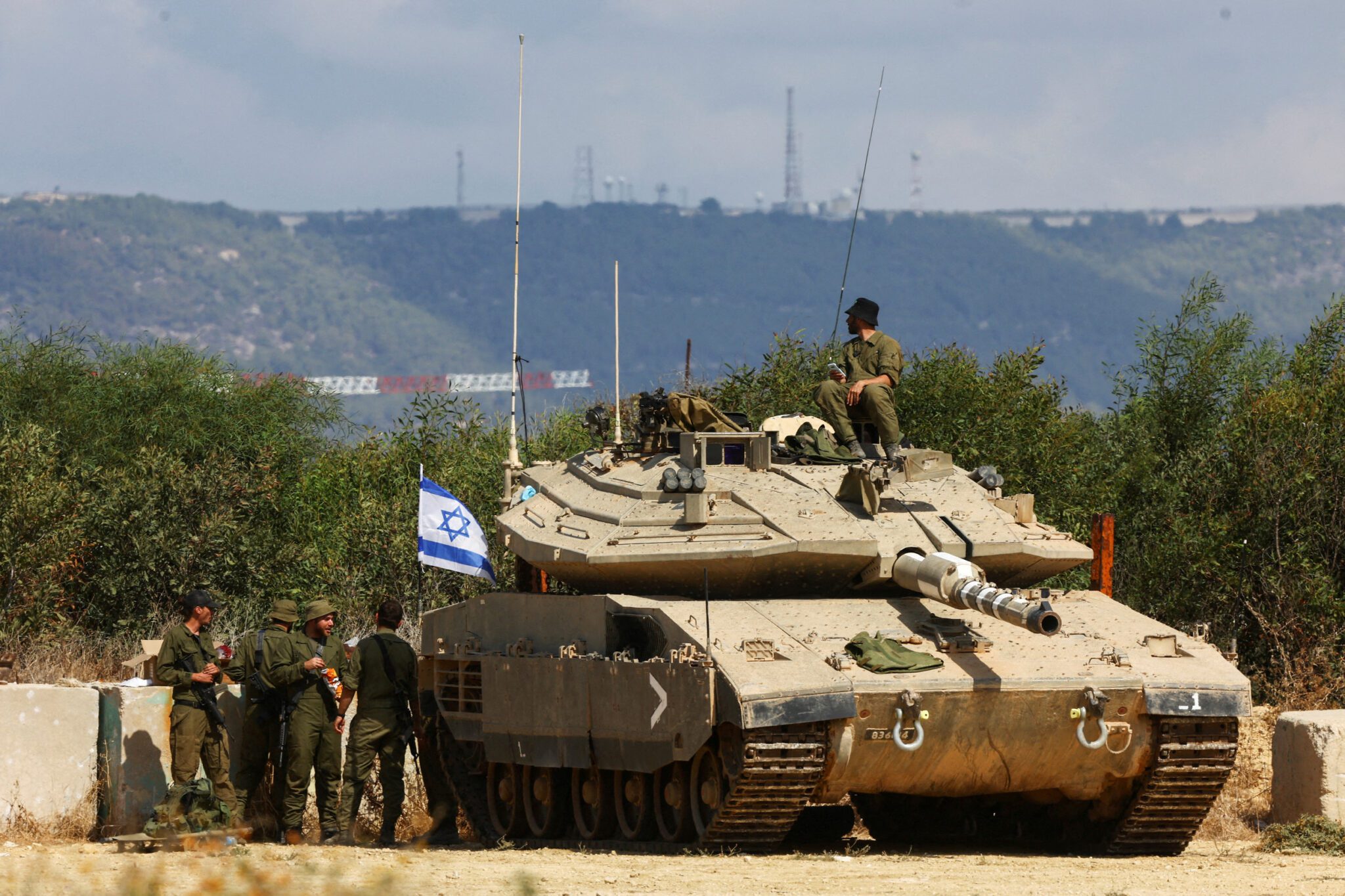 Israeli soldiers stand near to a tank near Israels border with Lebanon in northern Israel. 