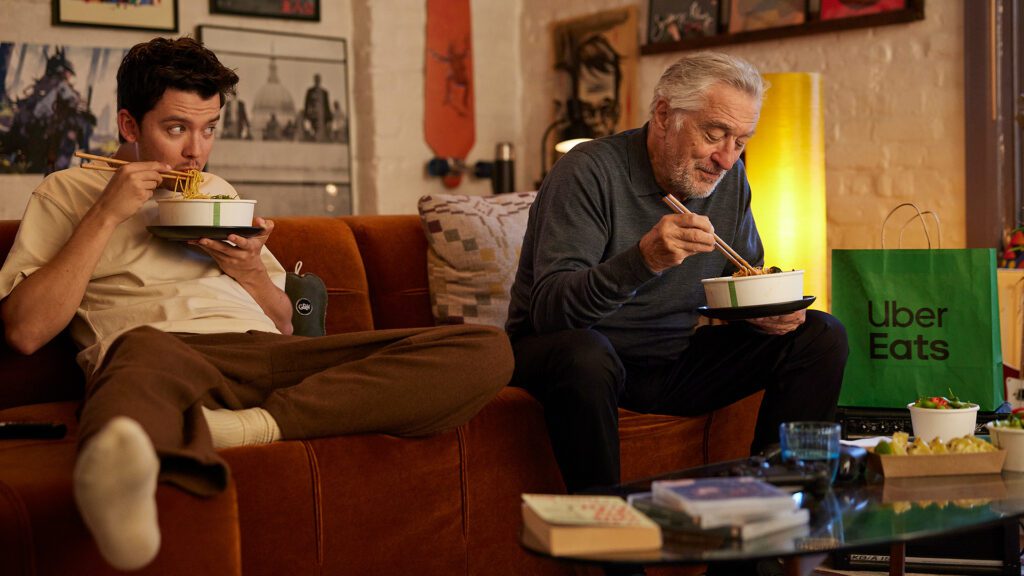 Robert De Niro and Asa Butterfield sat on a sofa eating food in the latest Uber One campaing.