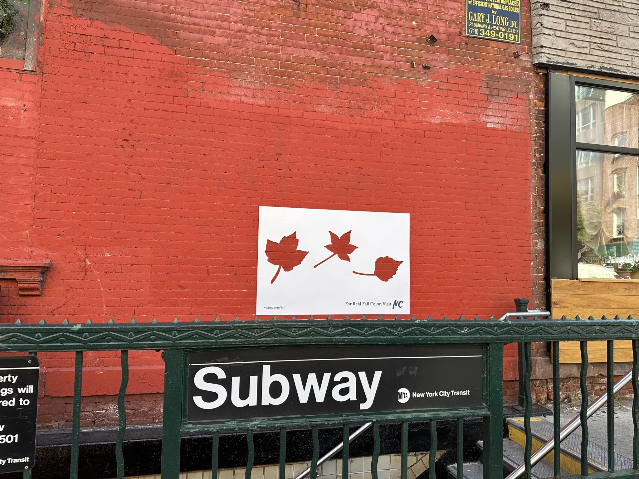 A sticker with leaf shaped cut outs has been placed over a red brick wall to demonstrate Visit North Carolina's Real Fall Campaign.