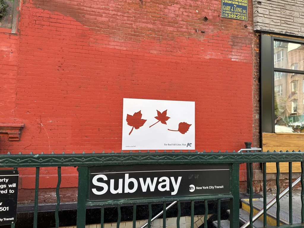 A sticker with leaf shaped cut outs has been placed over a red brick wall to demonstrate Visit North Carolina's Real Fall Campaign.