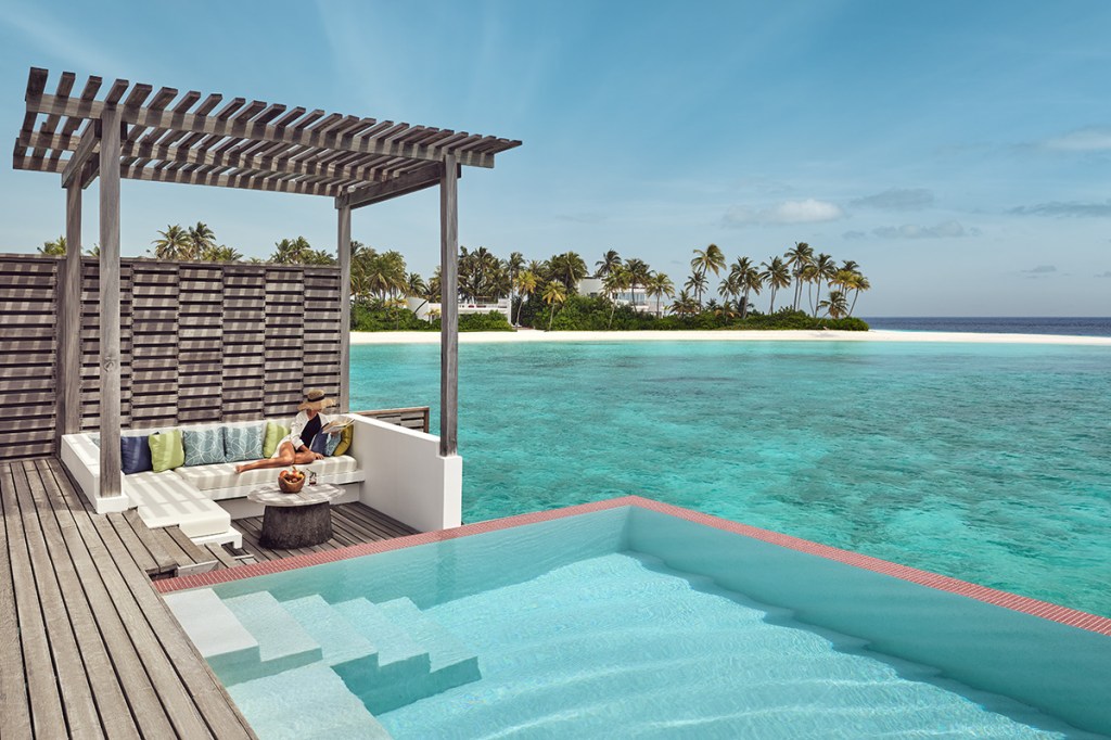 Woman reading next to the ocean and an infinity pool