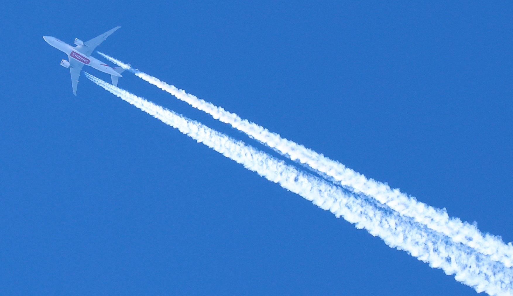 Vapour trails are seen behind an Emirates airline passenger plane as it flies over Manchester. 