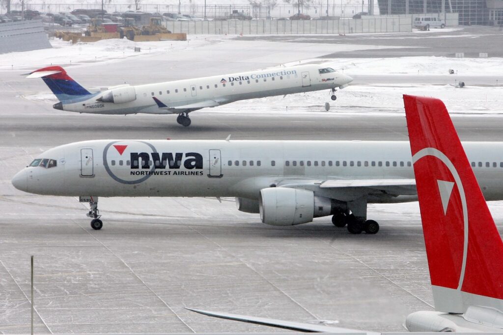 A Delta plane lands behind a Northwest plane