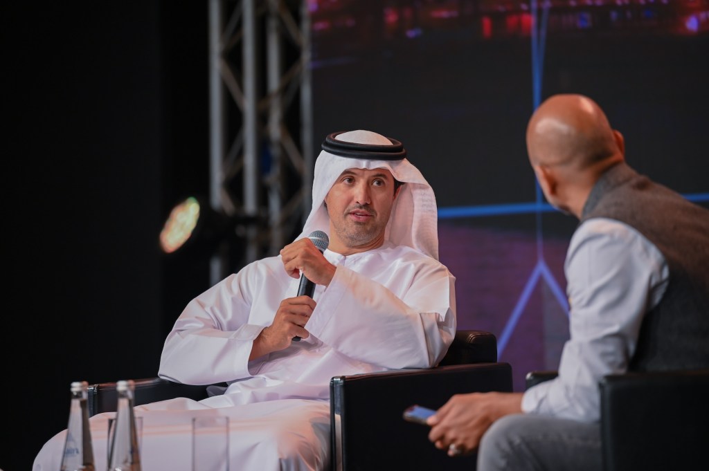 Two seated men holding a conversation on stage at a conference.