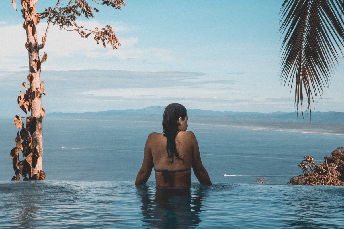 A woman swimming in infinity pool, overlooking the ocean.