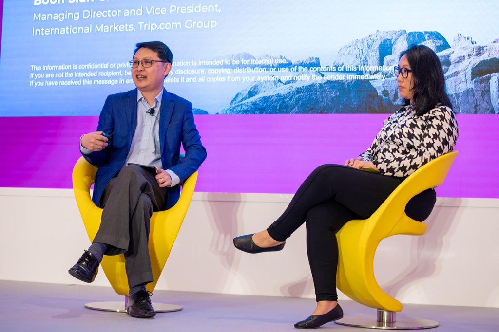 a man and a woman seated while speaking on stage