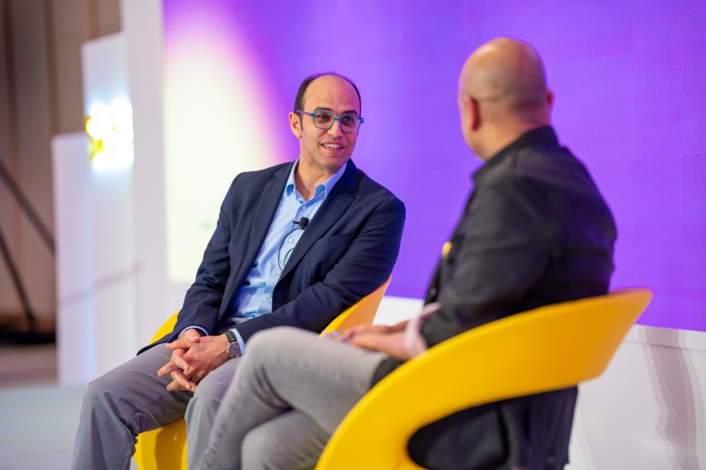 Two men speaking during a stage interview.