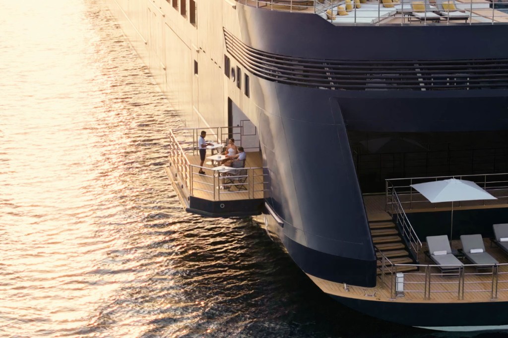 aerial drone view of guests dining on the marina terrace over water on the Evrima source ritz-carlton yacht collection