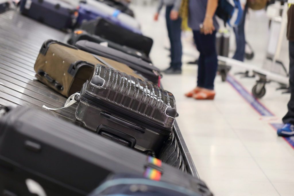 people picking up suitcase on luggage conveyor belt in the airport