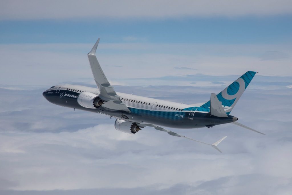 A Boeing 737 max plane in flight above the clouds