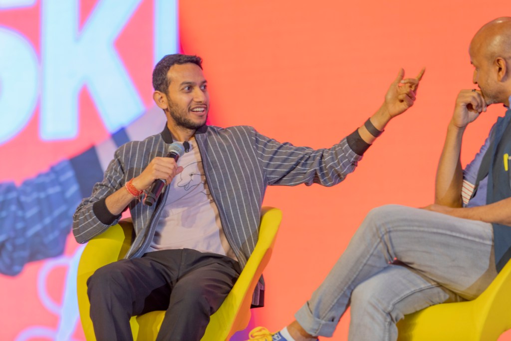 Two men speak on a stage.