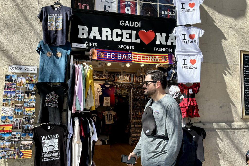 Exterior of a shop selling t-shirts with a man walking by