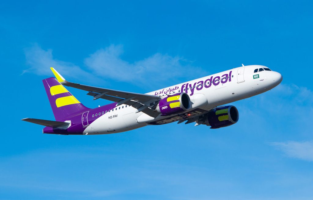 A Flyadeal Airbus A320neo plane flying in blue skies.