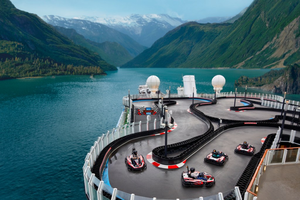 aerial view of a Go kart raceway for kids on top of a Norwegian Cruise Lines cruise ship in a waterway between mountains