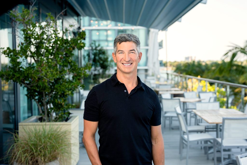 A photo of Kayak and OpenTable CEO Steve Hafner. The background is greenery and tables and chairs.