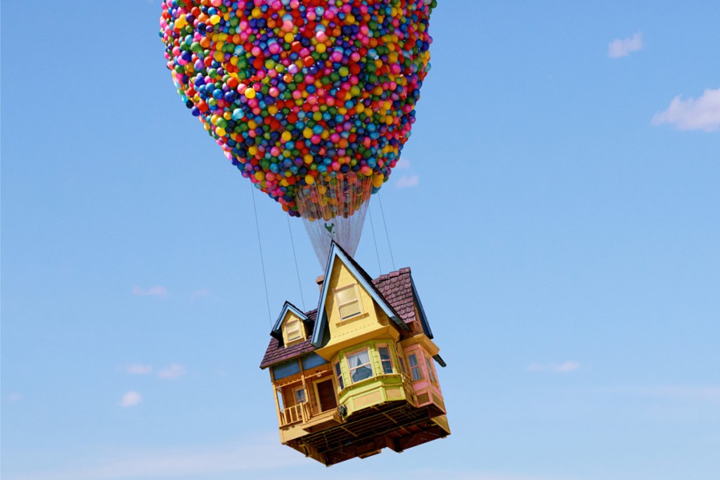 A yellow house and balloons being held aloft by a crane