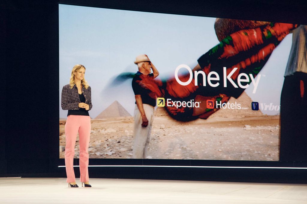 A woman speaking on stage at an Expedia conference in Las Vegas.