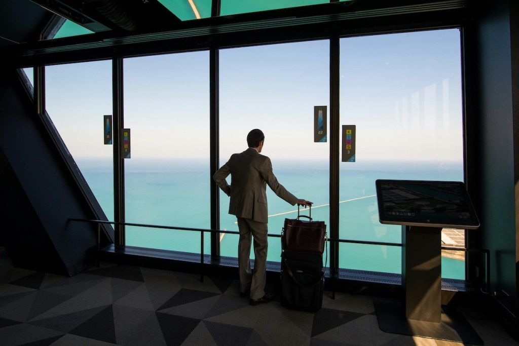 Man in suit with luggage overlooking lake