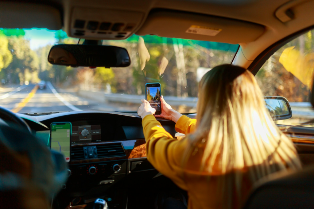 Blonde woman taking photo from front seat of car