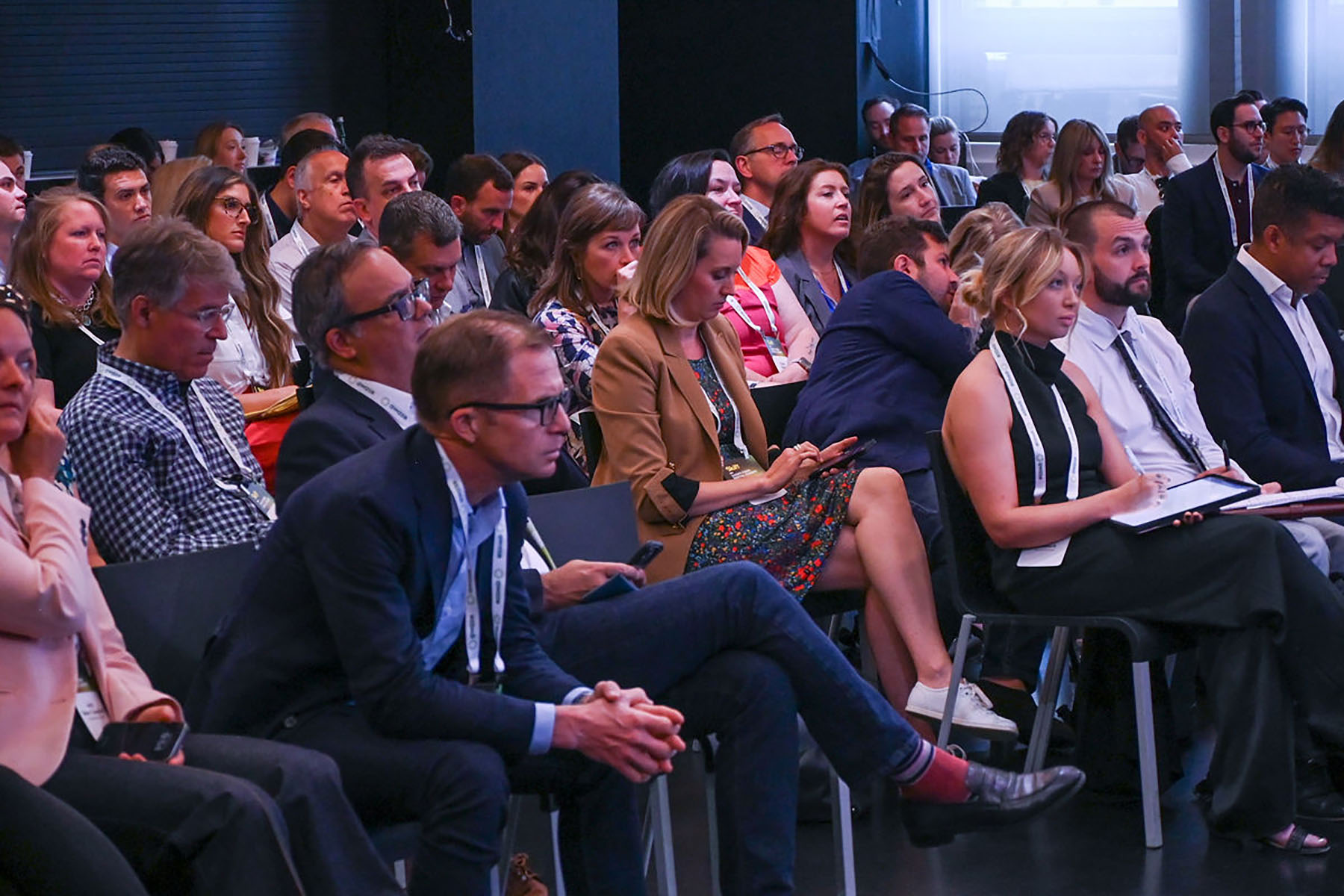 attendees seated in a theater space look at a stage