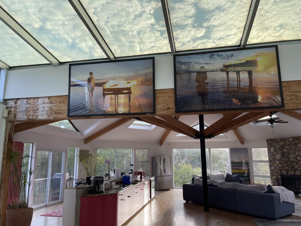 The inside of an Airbnb with beautiful paintings and a view of clouds through a skylight.