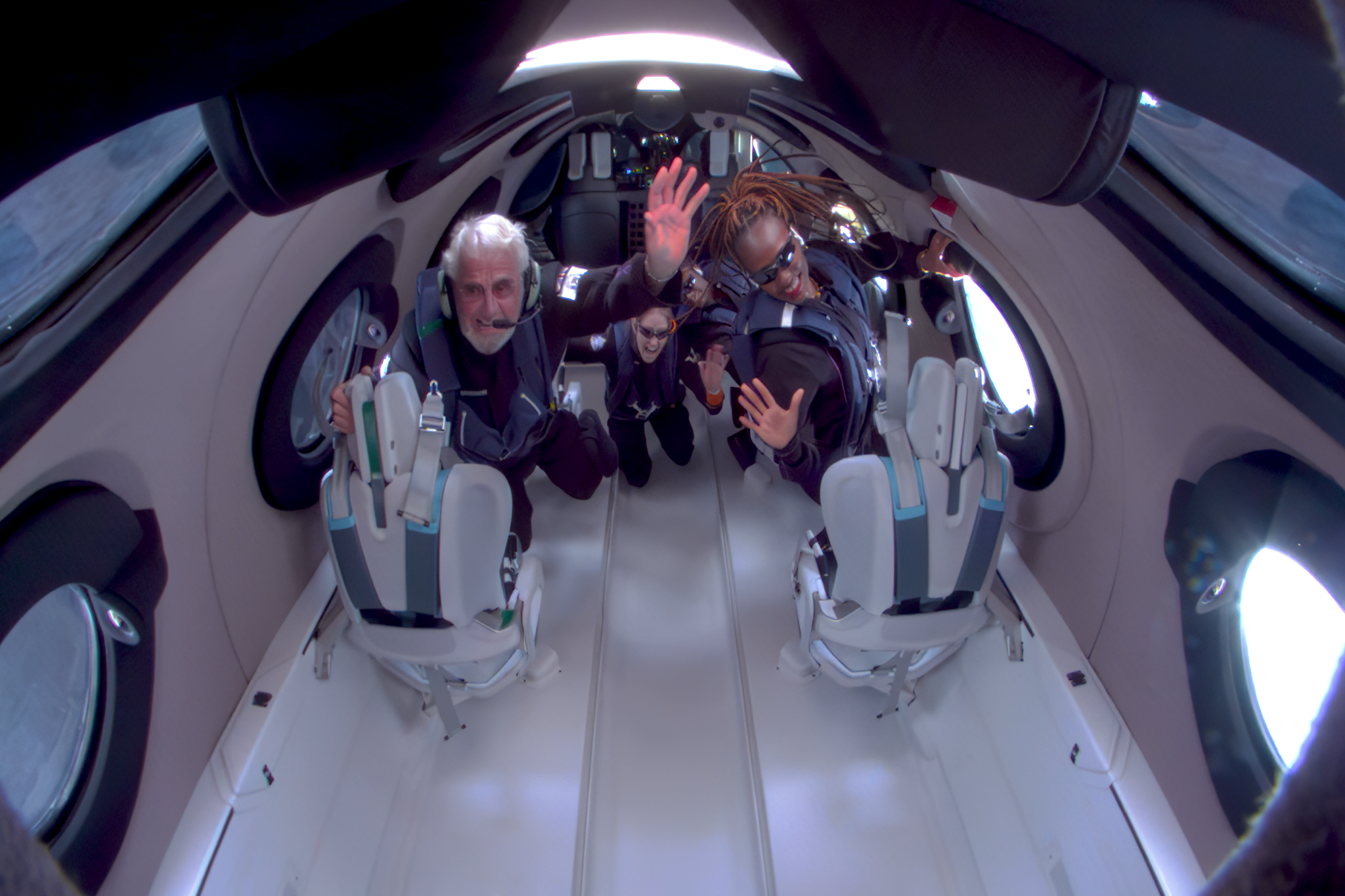 A crew waving to the camera on board one of Virgin Galactic's earlier flight