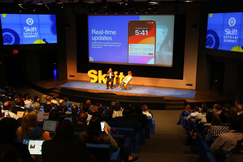 audience and stage at a conference with two people speaking on stage