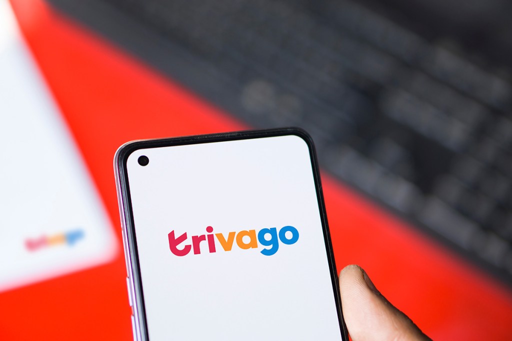 a hand holding a smartphone with the Trivago logo on the screen