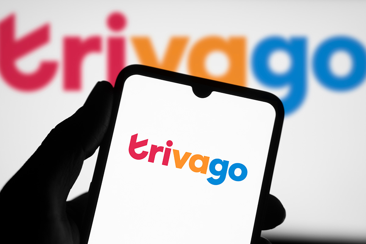 A hand holding a smartphone with the Trivago logo on the screen.