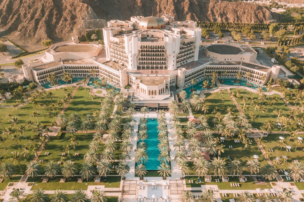 a garden in front of an elaborately luxurious Ritz Carlton hotel in Oman