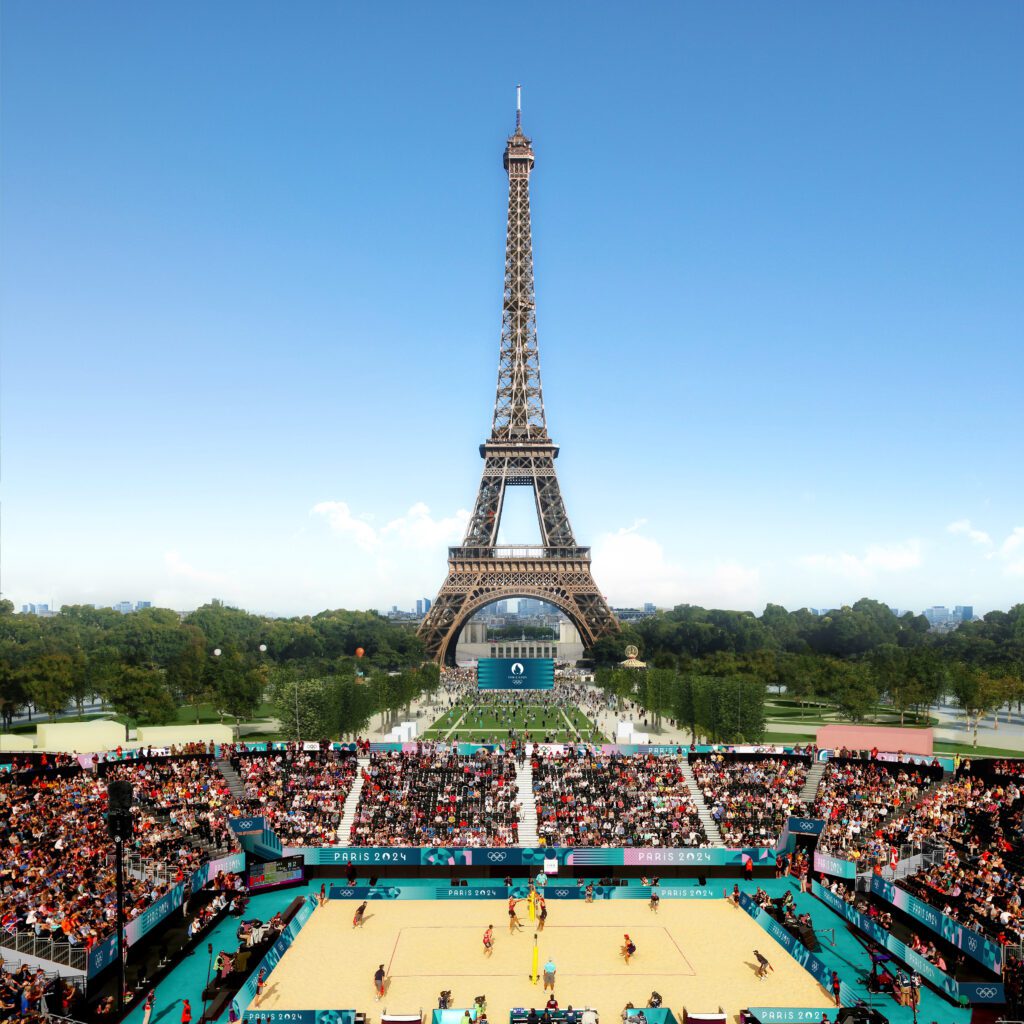 The Eiffel Tower in Paris 2024 with the Olympic teams playing sports in front of it as fans look on from the stadium. 