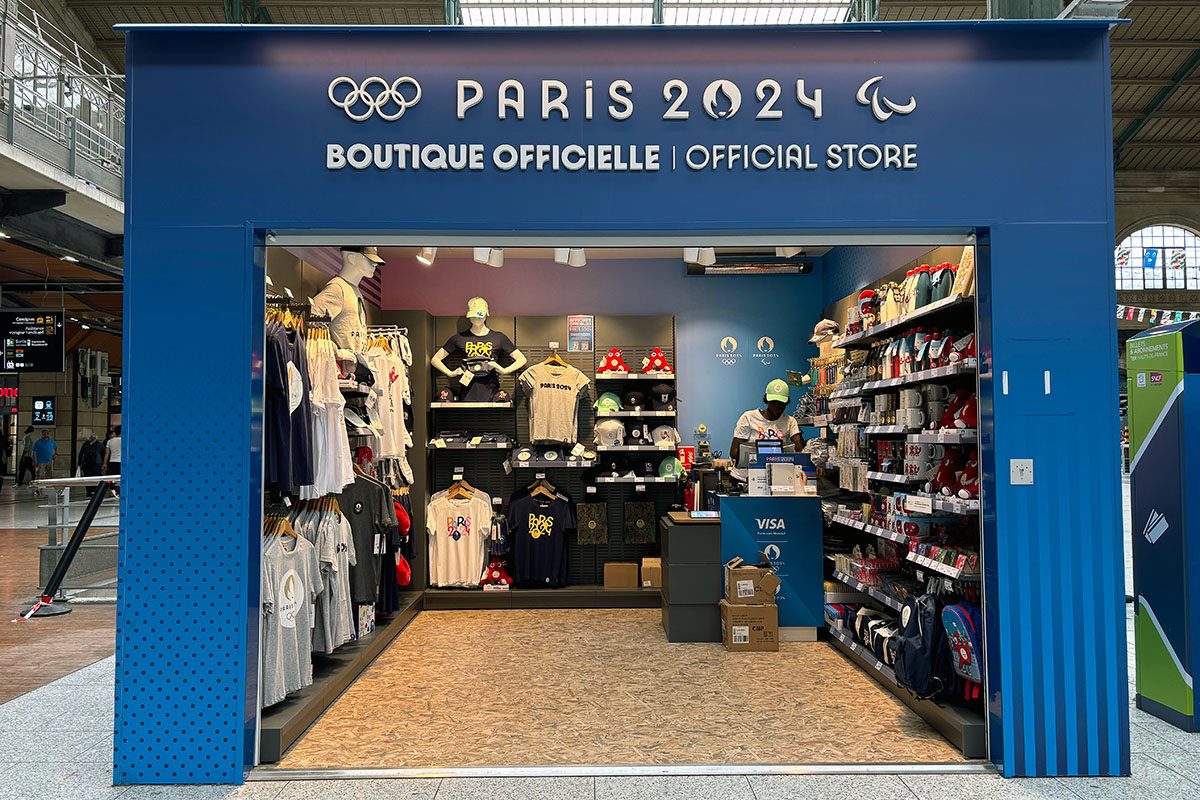 a large kiosk selling olympics merchandise inside a train station