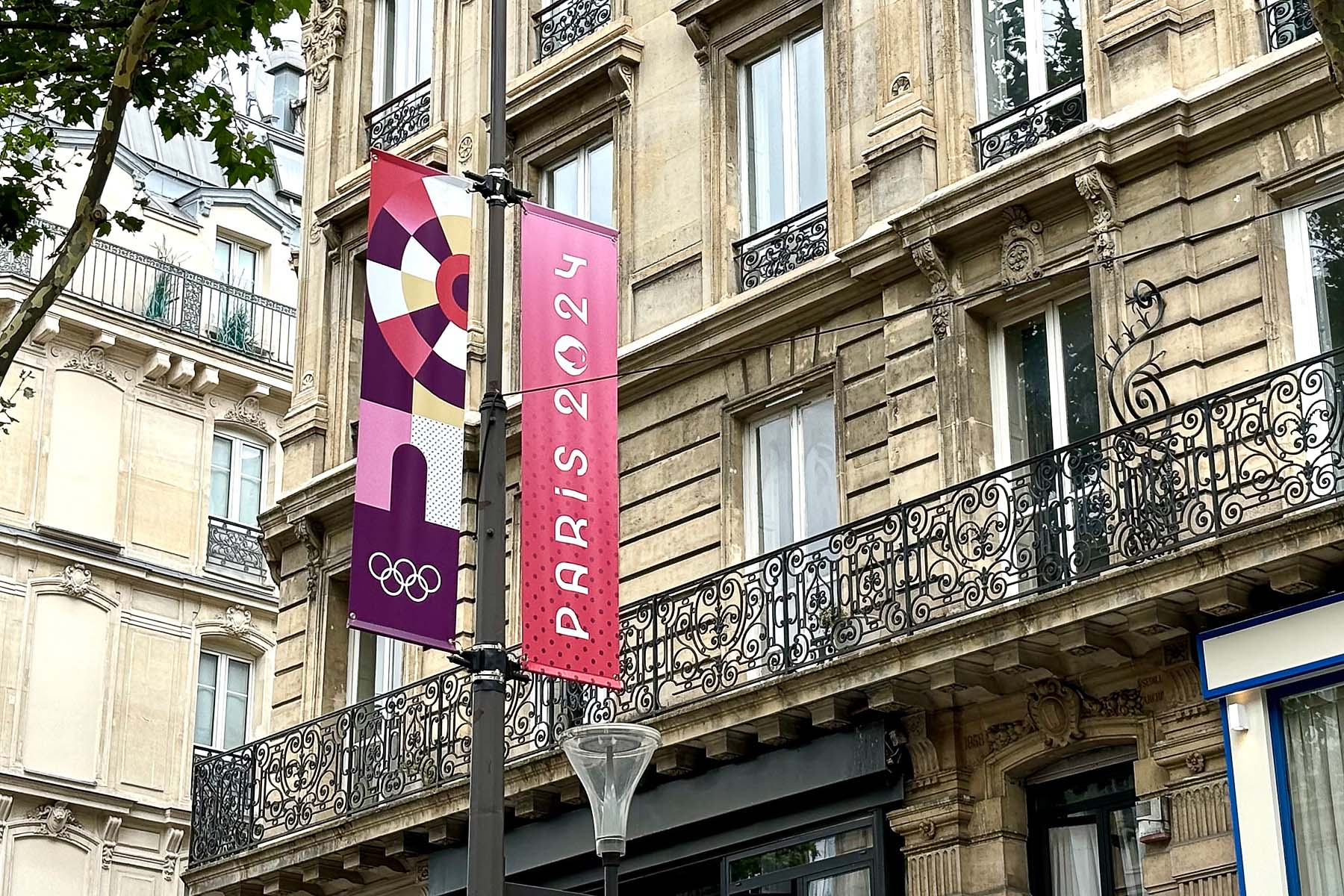 Flags promoting the Paris 2024 olympics hang from a lamppost in Paris.